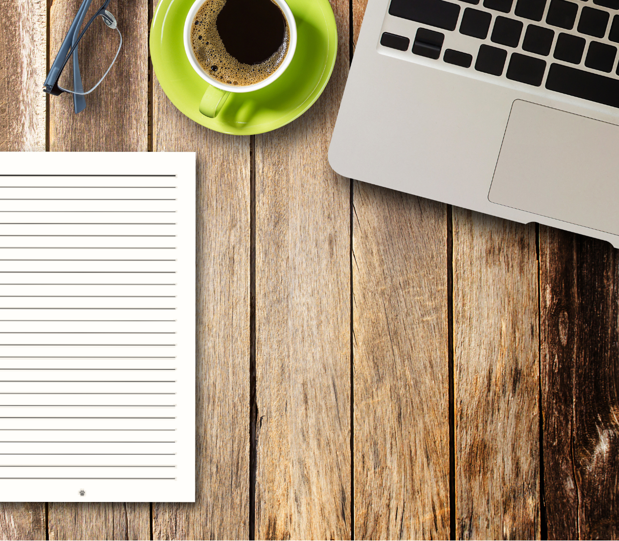 Notebook, coffee cup, and laptop on a wooden desk